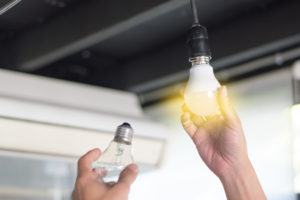 Man changing bulbs with new LED light bulb.